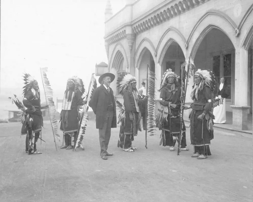 a black and white photo of Buffalo Bill Cody with a group of native Americans standing beside Cliff House in San Francisco California while touring